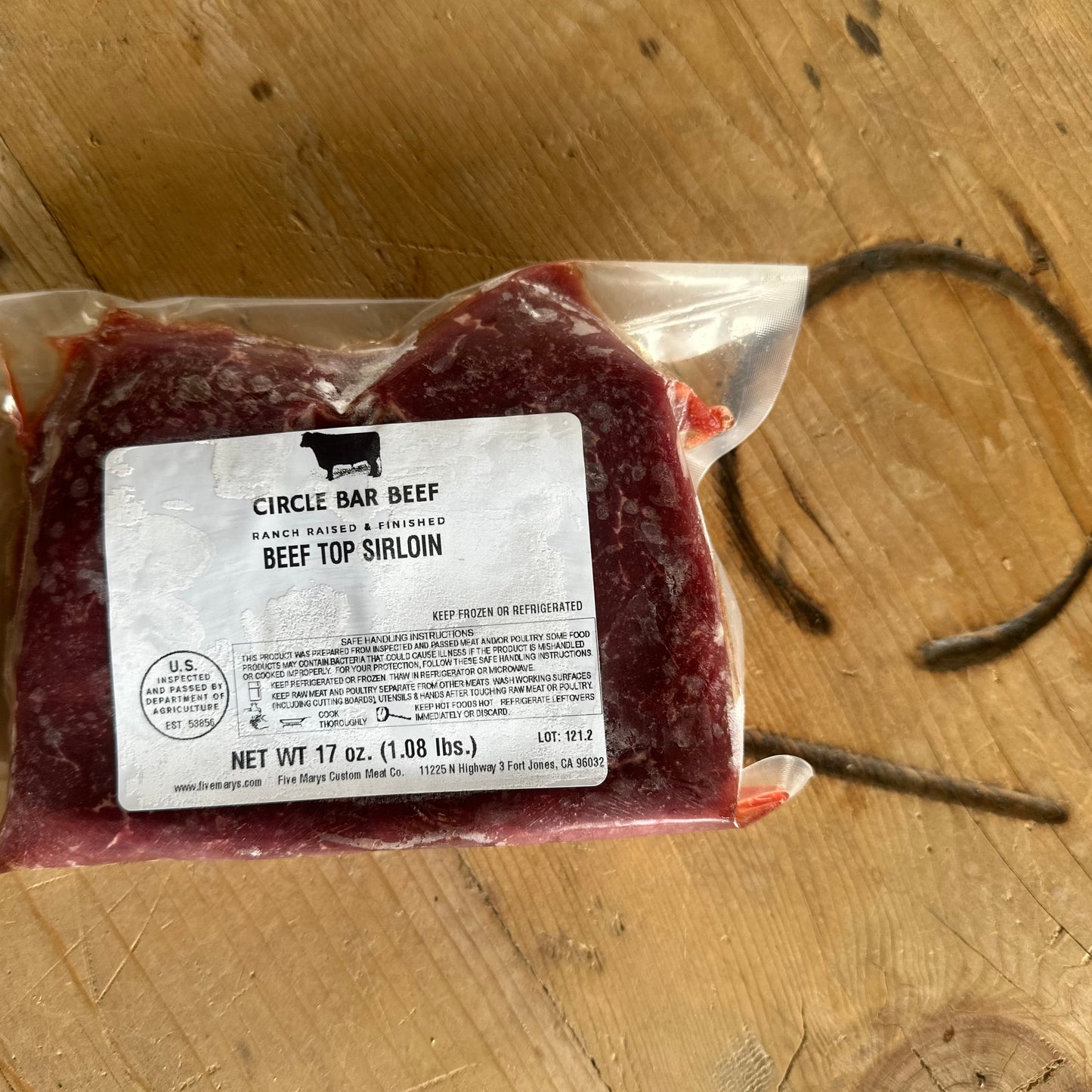 Packaged beef top sirloin with a label on a wooden surface