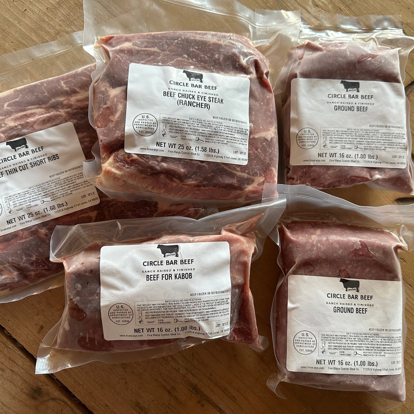 Packages of ground beef and beef chuck eye steaks on a wooden surface with Circle Bar Beef labels.