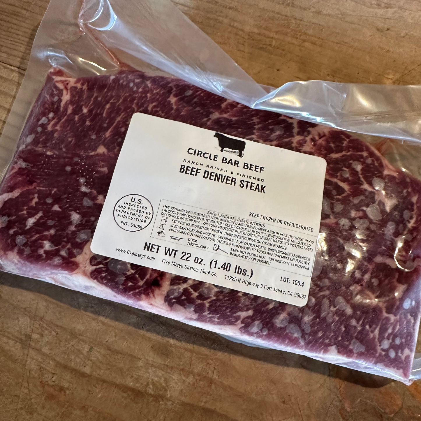 Packaged beef Denver steak with a label on a wooden surface