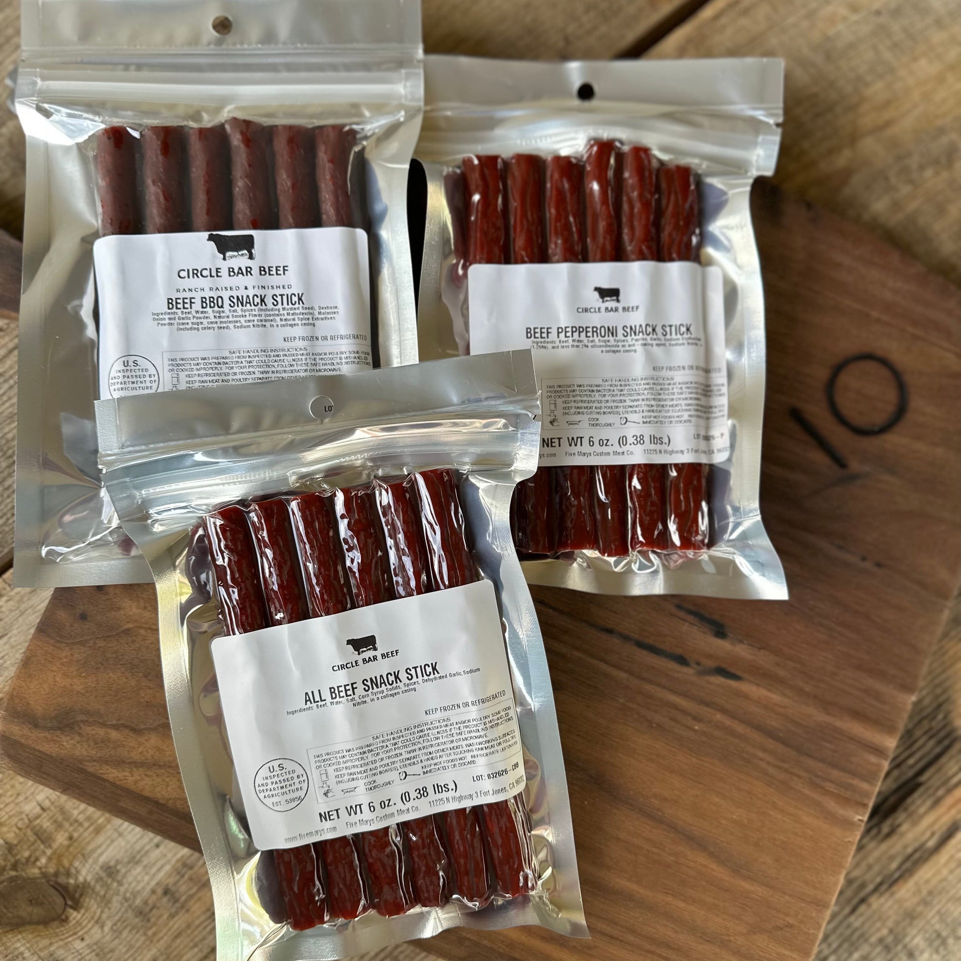 Three packages of beef snack sticks on a wooden surface
