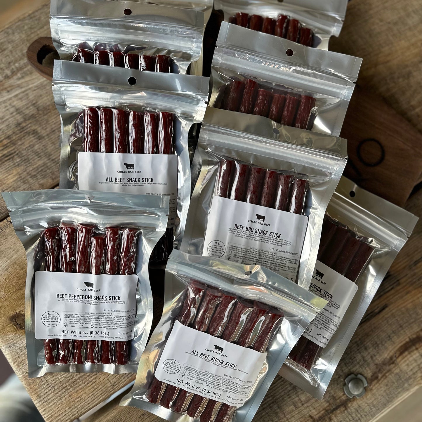 Multiple packages of beef snack sticks on a wooden surface