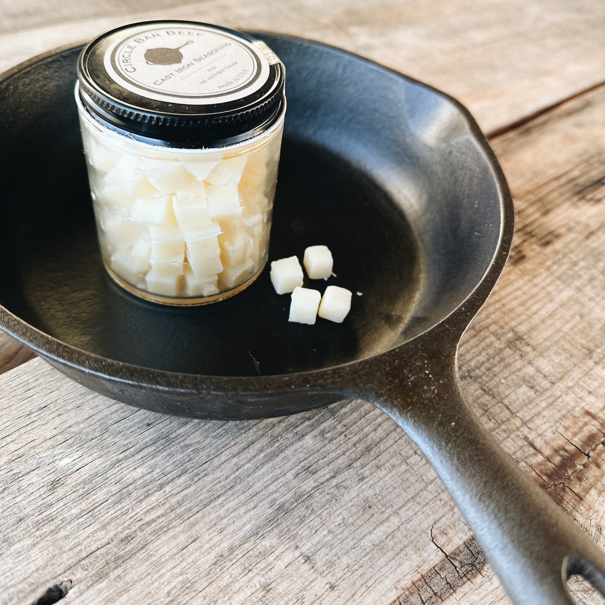Cast iron skillet with a jar of cubes on a wooden surface